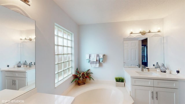 full bathroom featuring a bath, a sink, and two vanities