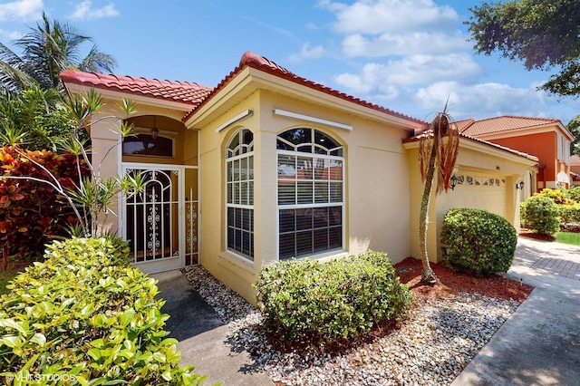 view of front of property featuring a garage, a tile roof, and stucco siding