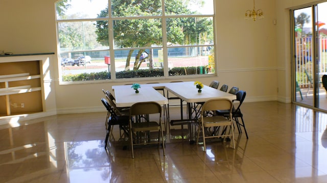 tiled dining area featuring a notable chandelier and baseboards