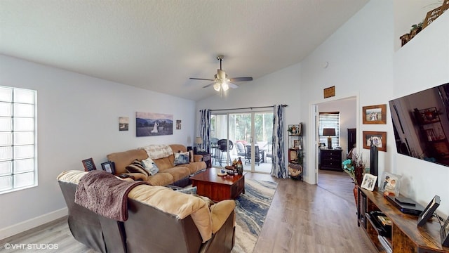 living area with baseboards, lofted ceiling, light wood-style flooring, ceiling fan, and a textured ceiling