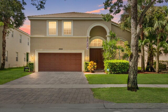 mediterranean / spanish-style home featuring a garage and a lawn