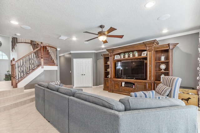 tiled living room with ceiling fan, a textured ceiling, and ornamental molding