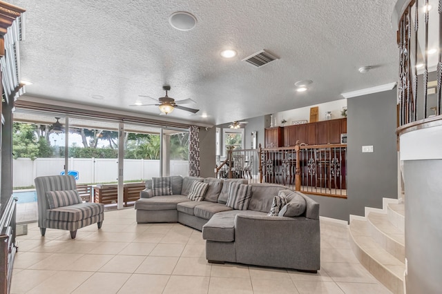 living room featuring ceiling fan, a textured ceiling, and light tile patterned floors