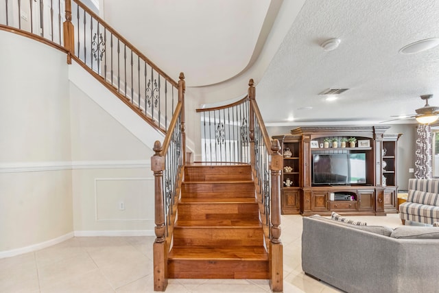 stairs with a textured ceiling, ceiling fan, and tile patterned floors