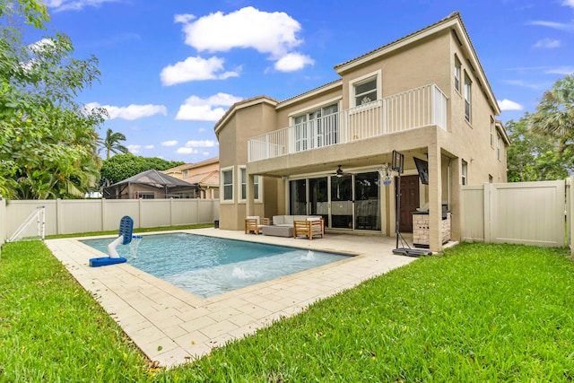 back of property featuring a balcony, a fenced in pool, pool water feature, a lawn, and an outdoor hangout area