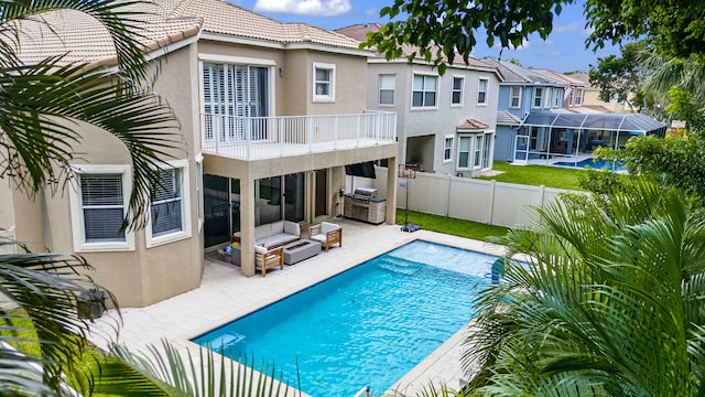 rear view of property featuring a balcony, a fenced in pool, and a patio area