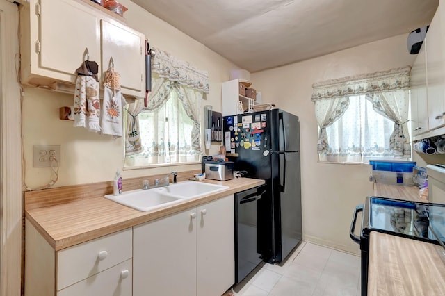 kitchen with white cabinetry, sink, light tile patterned flooring, and black appliances