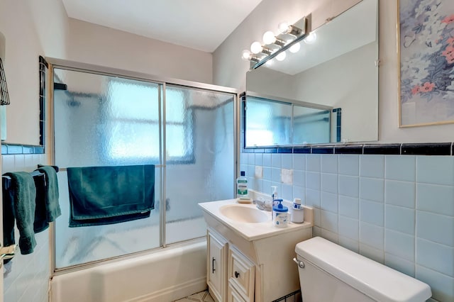 bathroom with toilet, shower / bath combination with glass door, tile walls, and vanity