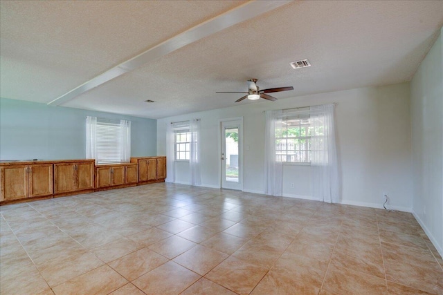 unfurnished room featuring ceiling fan, plenty of natural light, and a textured ceiling