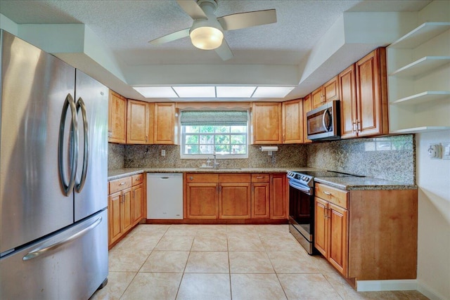 kitchen featuring sink, light tile patterned floors, stainless steel appliances, light stone countertops, and decorative backsplash