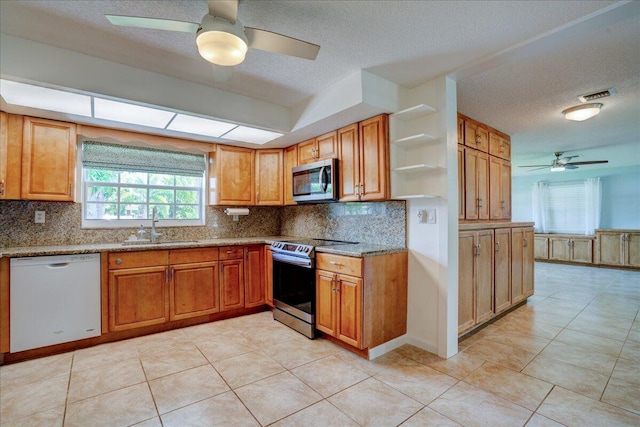 kitchen with tasteful backsplash, stainless steel appliances, light stone countertops, and sink