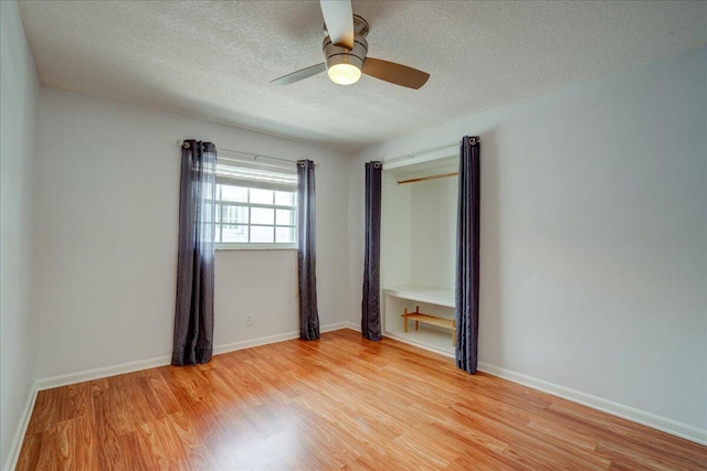 unfurnished room with ceiling fan, a textured ceiling, and light wood-type flooring