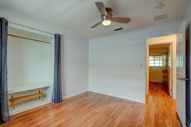 empty room featuring ceiling fan, light hardwood / wood-style flooring, and a textured ceiling