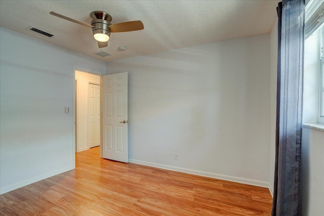 unfurnished room featuring ceiling fan, a textured ceiling, and light wood-type flooring