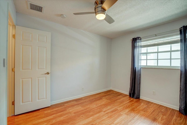 empty room with ceiling fan, a textured ceiling, and light wood-type flooring