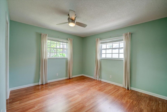 spare room featuring ceiling fan, a healthy amount of sunlight, a textured ceiling, and light wood-type flooring