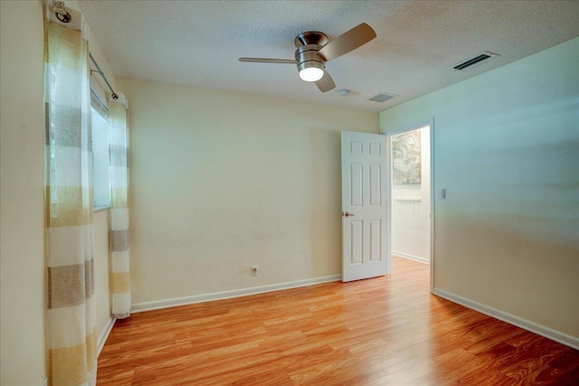 spare room with ceiling fan, light hardwood / wood-style floors, and a textured ceiling