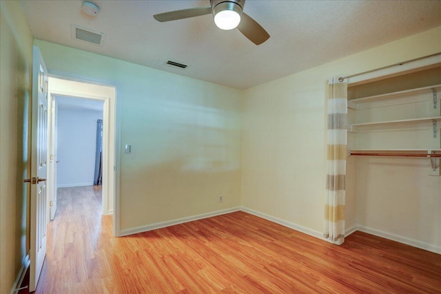 unfurnished bedroom featuring ceiling fan, a textured ceiling, a closet, and light wood-type flooring