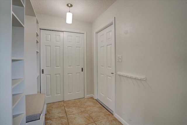 doorway featuring light tile patterned flooring and a textured ceiling