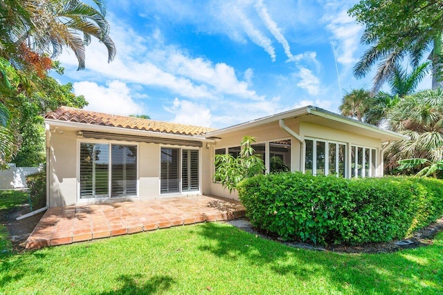 back of property featuring a lawn and a patio