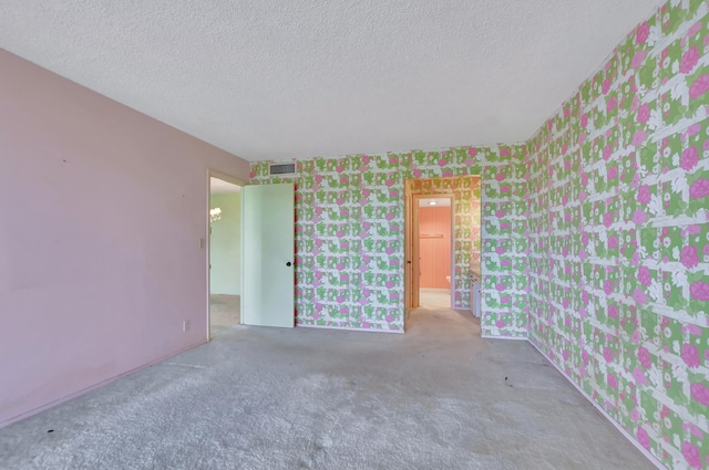 unfurnished room with a textured ceiling and carpet flooring