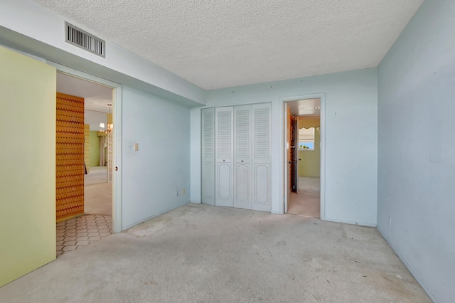 unfurnished bedroom featuring a textured ceiling, carpet, a chandelier, and ensuite bathroom