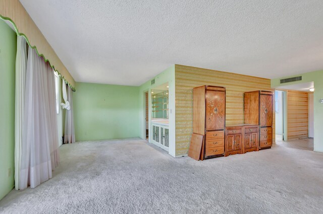 unfurnished room with light carpet and a textured ceiling