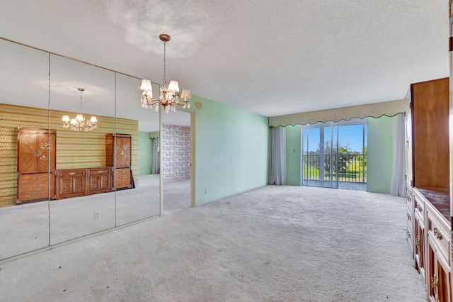 unfurnished living room featuring carpet flooring, a textured ceiling, and an inviting chandelier