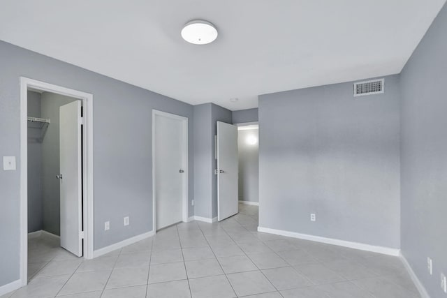 unfurnished bedroom featuring light tile patterned floors, a walk in closet, and a closet