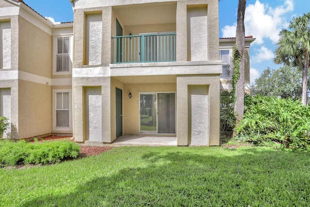 rear view of house with a balcony and a lawn