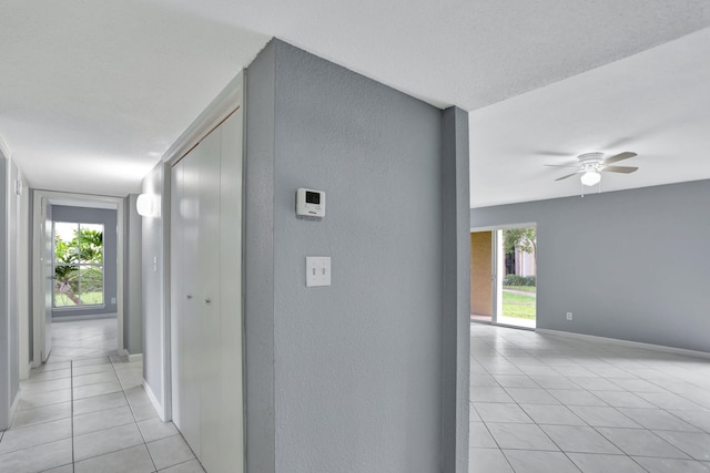 hall with a textured ceiling and light tile patterned floors