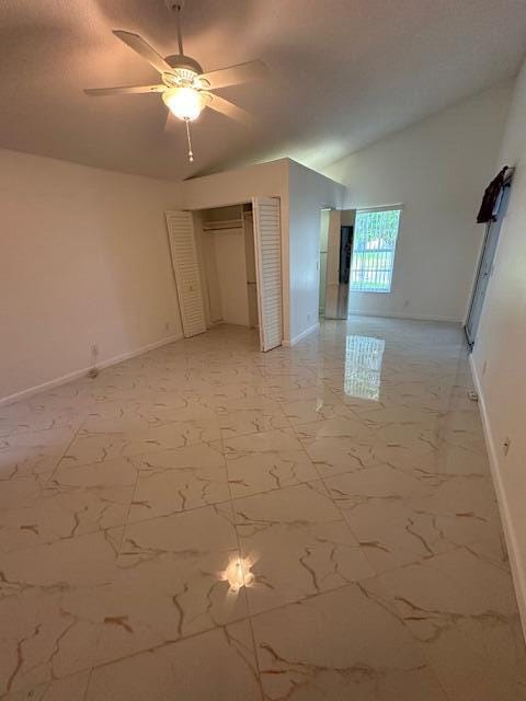 unfurnished bedroom featuring ceiling fan, lofted ceiling, and a closet