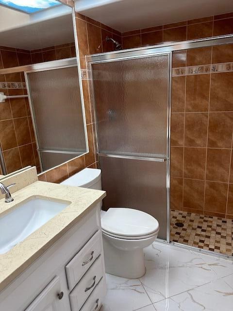 bathroom with vanity, toilet, and a shower with door