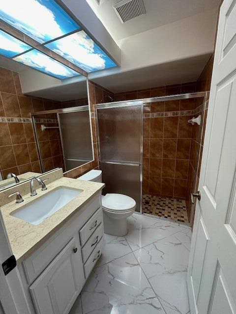 bathroom featuring vanity, toilet, and an enclosed shower