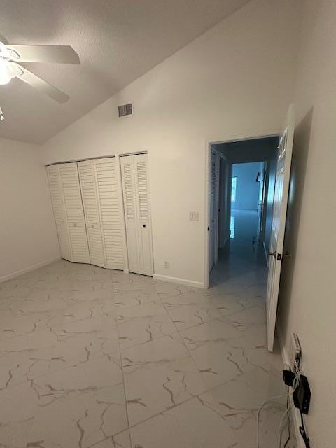 unfurnished bedroom with multiple closets, ceiling fan, and lofted ceiling