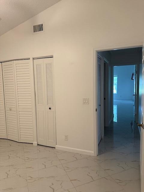 unfurnished bedroom featuring lofted ceiling and multiple closets