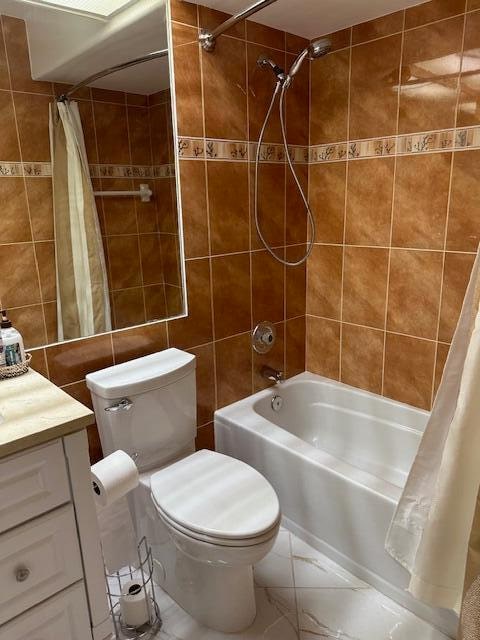 full bathroom with shower / bathtub combination with curtain, vanity, tile walls, and toilet