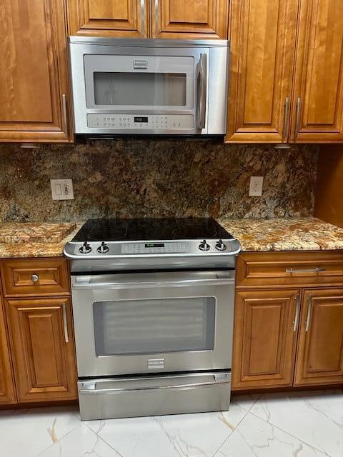 kitchen with stone counters, decorative backsplash, and appliances with stainless steel finishes