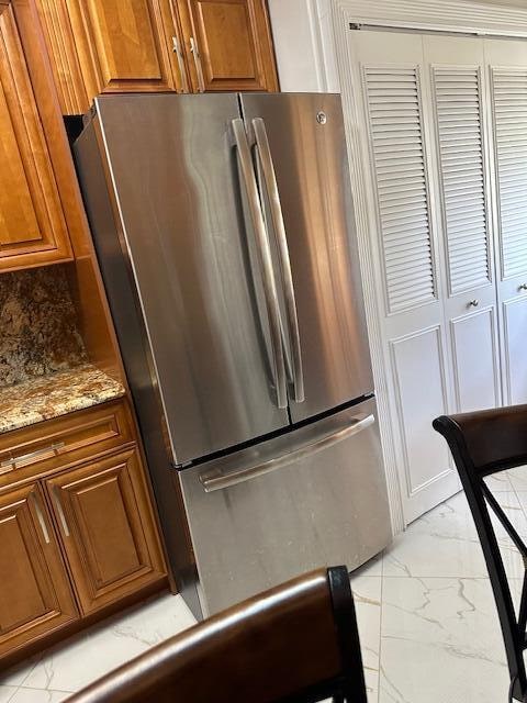 kitchen featuring stainless steel refrigerator and light stone counters