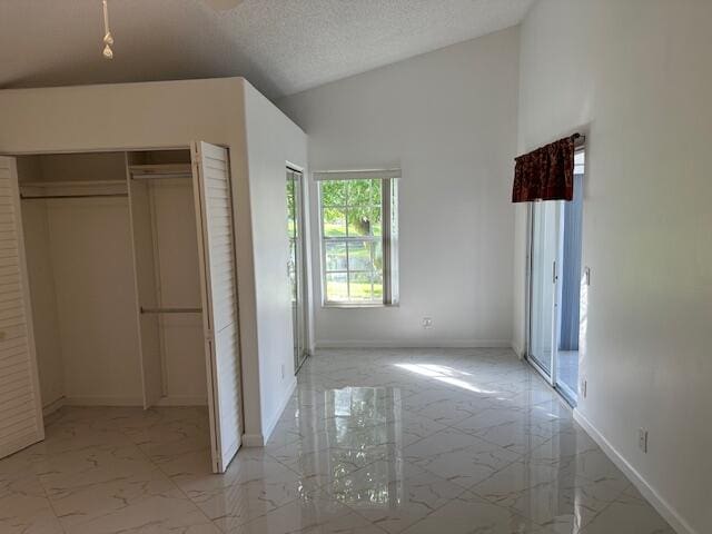 unfurnished bedroom with a closet, high vaulted ceiling, and a textured ceiling