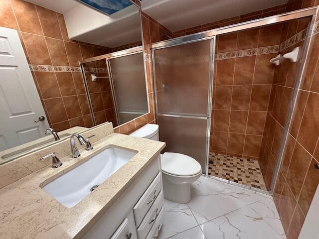 bathroom featuring vanity, toilet, walk in shower, and tile walls