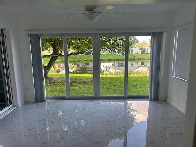 doorway with ceiling fan and a water view