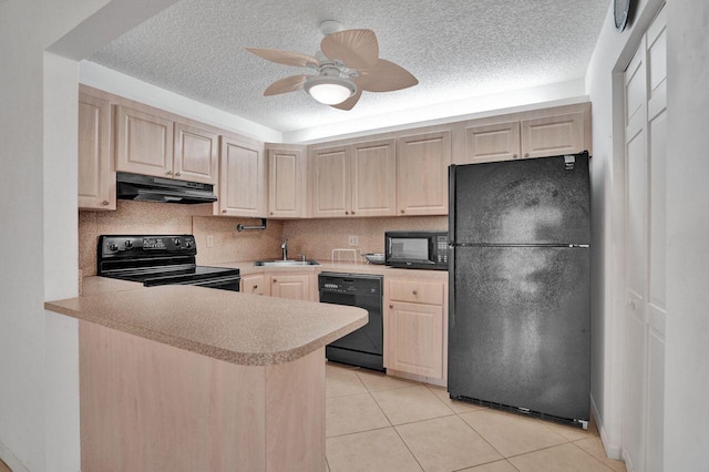 kitchen featuring light countertops, light brown cabinetry, a sink, under cabinet range hood, and black appliances