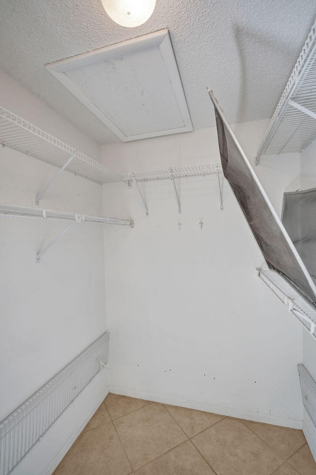 spacious closet featuring light tile patterned floors and attic access