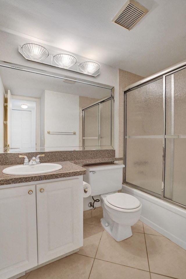 full bathroom featuring tile patterned floors, shower / bath combination with glass door, vanity, and toilet