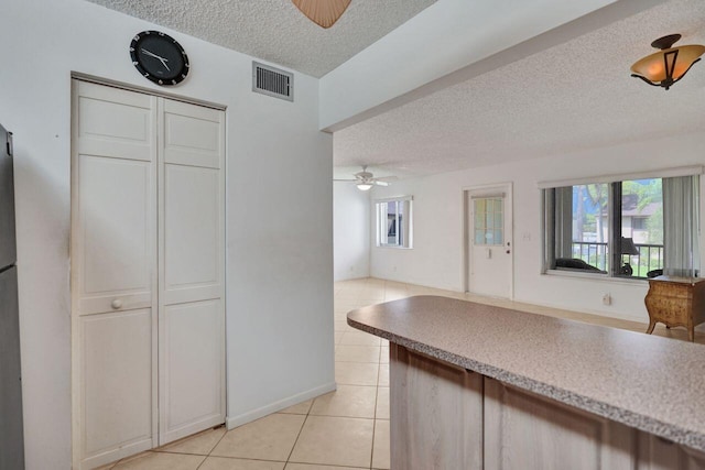 kitchen featuring light tile patterned floors, ceiling fan, a textured ceiling, visible vents, and open floor plan