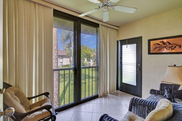 living room featuring a textured wall, ceiling fan, and light tile patterned flooring