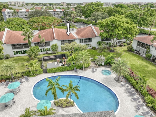community pool with a hot tub and a yard