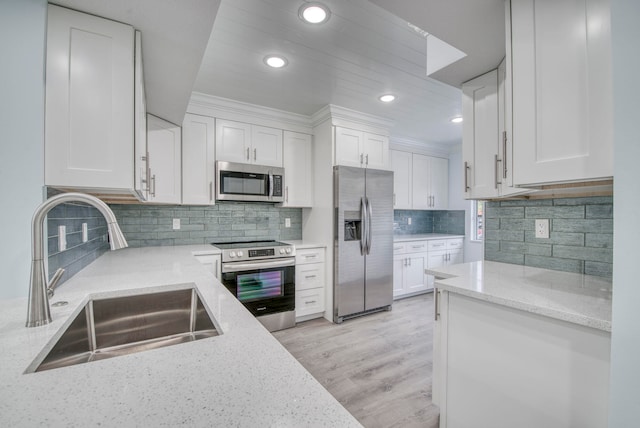 kitchen featuring stainless steel appliances, white cabinets, light wood-type flooring, sink, and tasteful backsplash