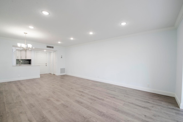 unfurnished living room featuring ornamental molding, a chandelier, and light hardwood / wood-style floors